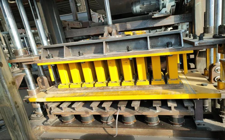 Upper mould pressure head, with yellow press feet, positioned above the lower mould in the main machine.
